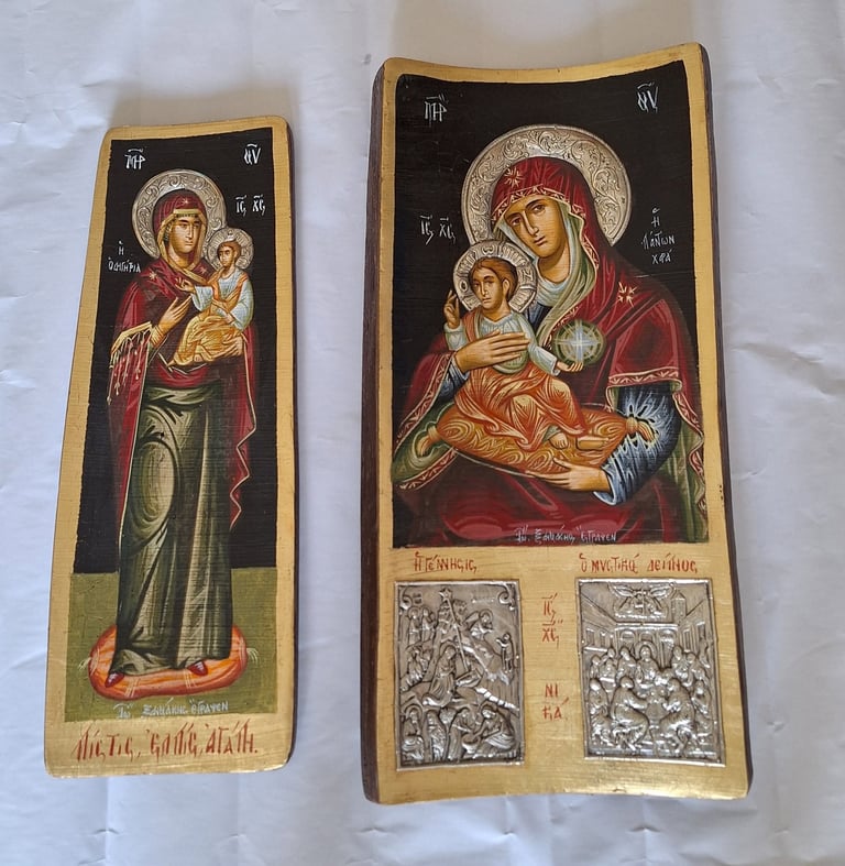 Two Orthodox religious icons depicting the Virgin Mary and Child Jesus with halos, featuring gold trim and Cyrillic text on aged wooden panels