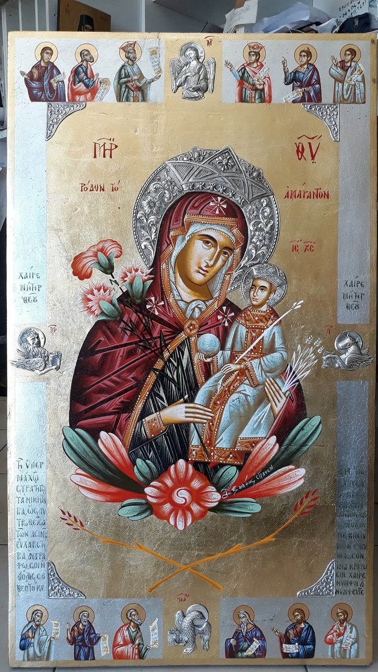 Orthodox Christian religious icon of Mary holding the Christ Child, surrounded by saints and flowers on gold leaf