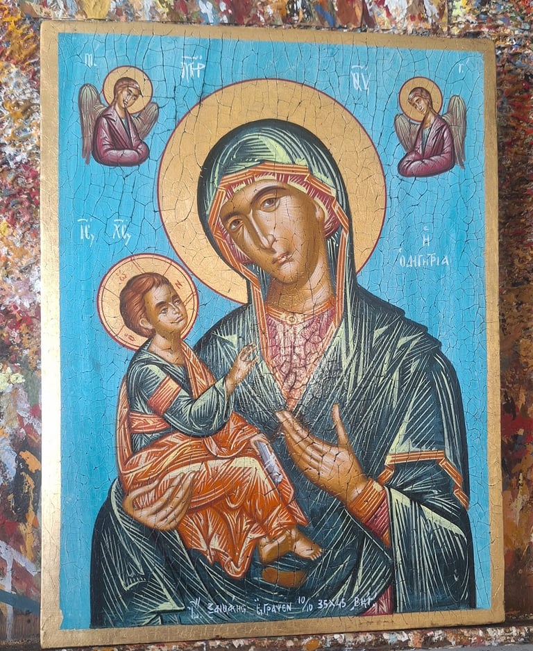 Orthodox religious icon depicting Mary holding Christ Child with halo, blue background, gold accents, and angels above