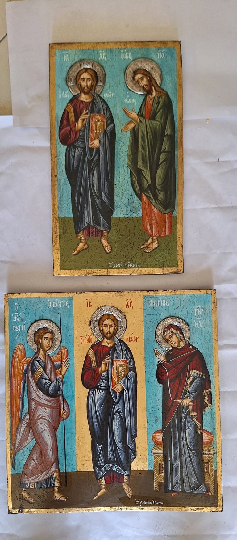 Two Byzantine religious icons displayed on white surface, featuring painted figures with halos in traditional Christian Orthodox iconographic style