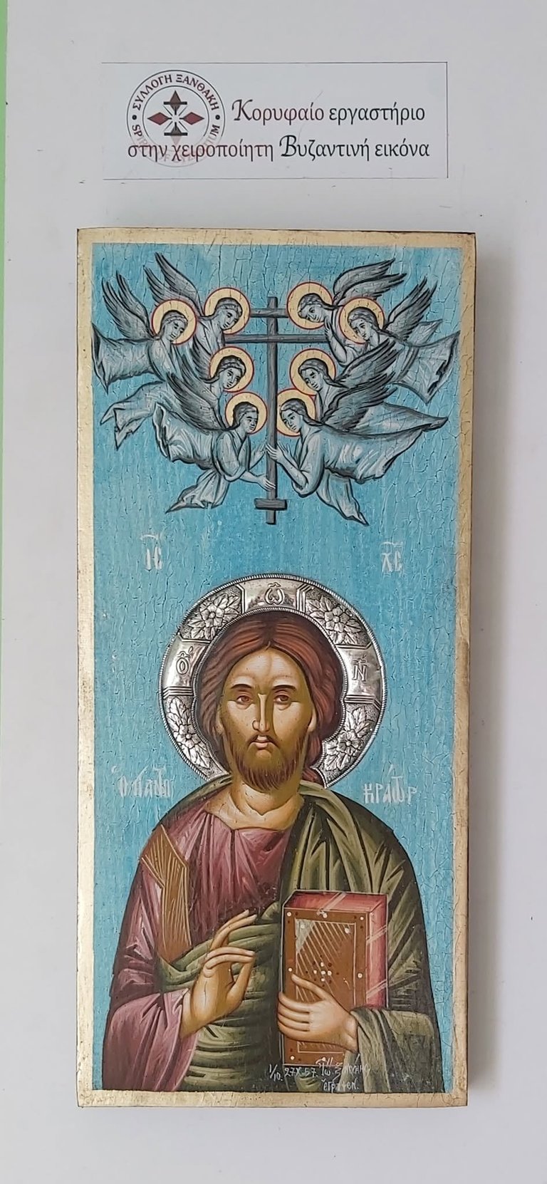 Byzantine religious icon depicting Christ holding a book, with six winged angels above and a silver halo, on wooden panel with Greek text