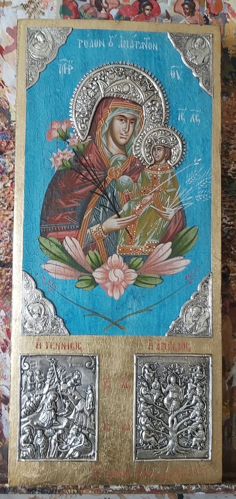 Orthodox religious icon featuring Virgin Mary and Christ Child with silver ornaments on bright blue background and decorative silver plaques below