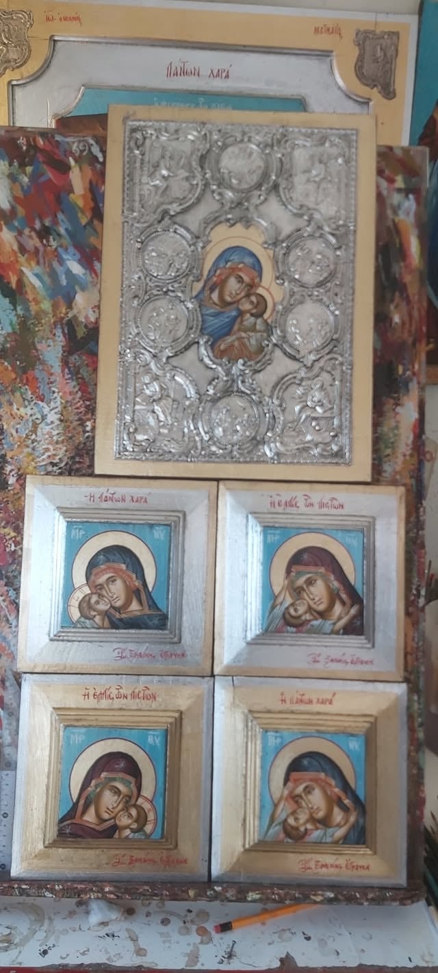 Religious icon display with ornate silver-trimmed central Madonna and Child image above four smaller framed icons featuring various Madonna portraits