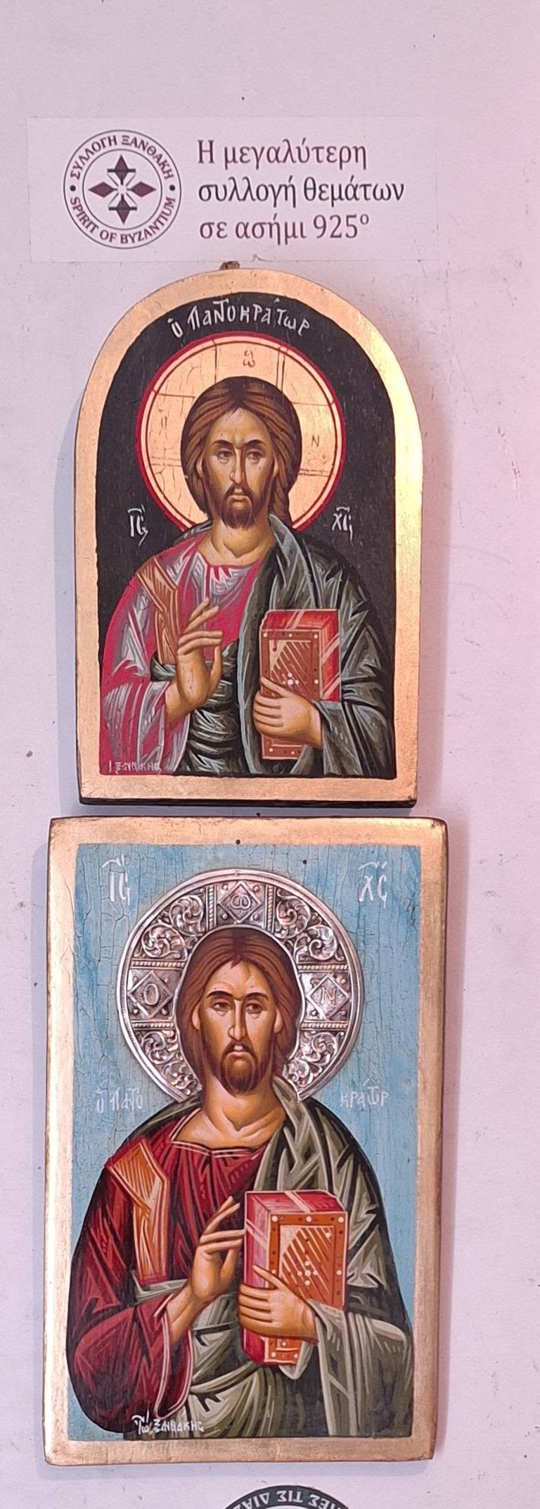 Two Byzantine-style religious icons depicting Jesus Christ with halo and red book, mounted on wooden plaques against a light purple background