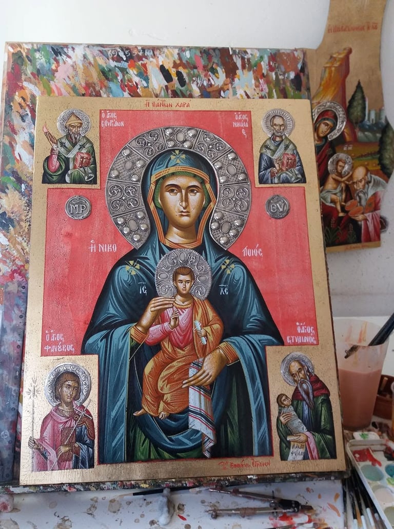 Orthodox religious icon featuring Virgin Mary holding Christ Child with ornate halo and surrounding saints on red background