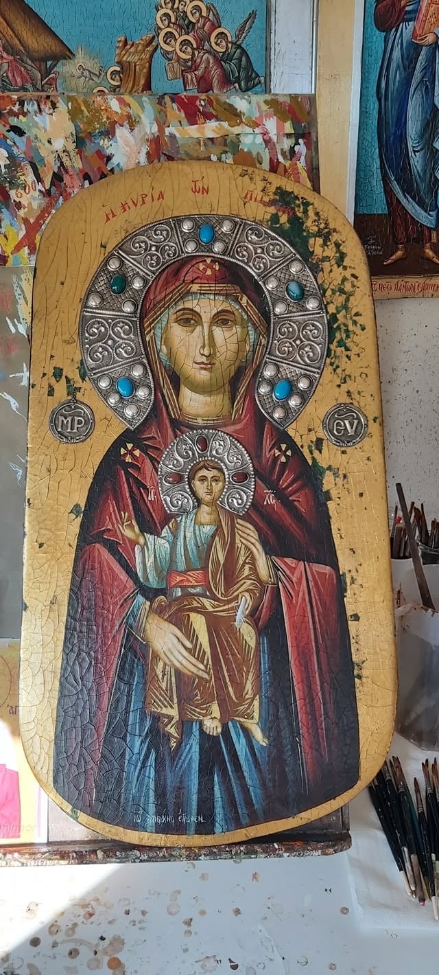 Eastern Orthodox religious icon on aged wooden panel depicting Virgin Mary with Christ Child, ornate silver halo with blue stones