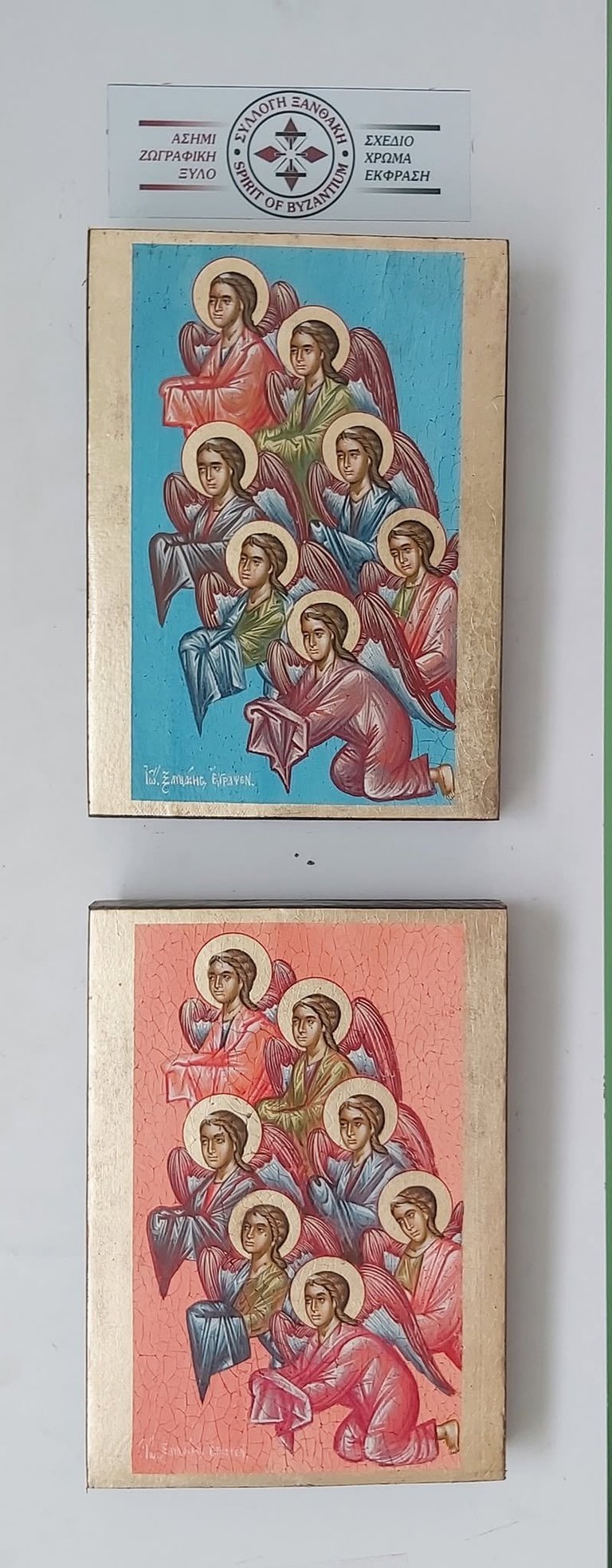 Two Byzantine religious icons depicting seven winged angels in hierarchical arrangement, one with blue background and one with pink background, mounted on wooden panels with Greek text and official seal