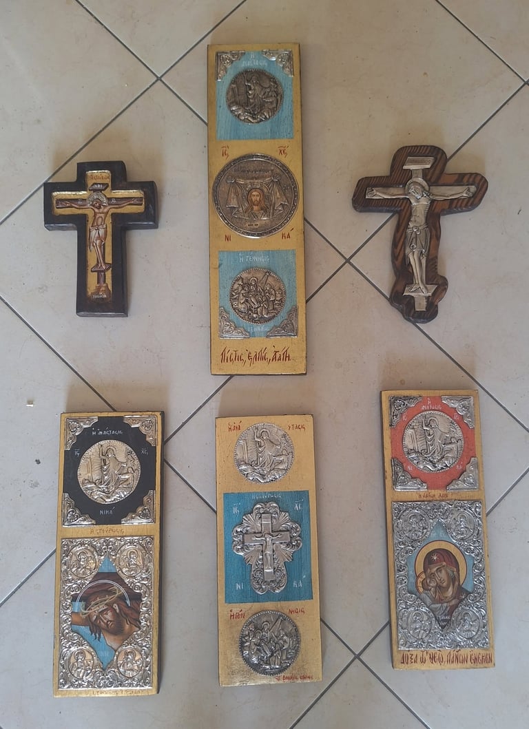 Six religious wall ornaments displayed on white tile, including two brown wooden crucifix crosses and four wooden panels with embossed religious medallions and icons.