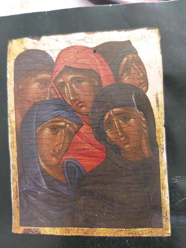 Ancient religious icon painting on wood showing five faces with halos in muted earth tones and red, with gold leaf border, displaying visible age and cracking