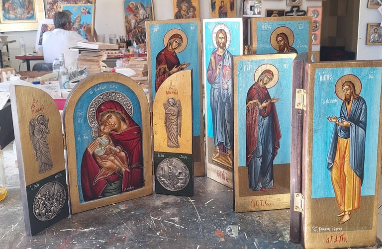 Religious wooden icons with painted Orthodox Christian figures displayed in an artist workshop or studio