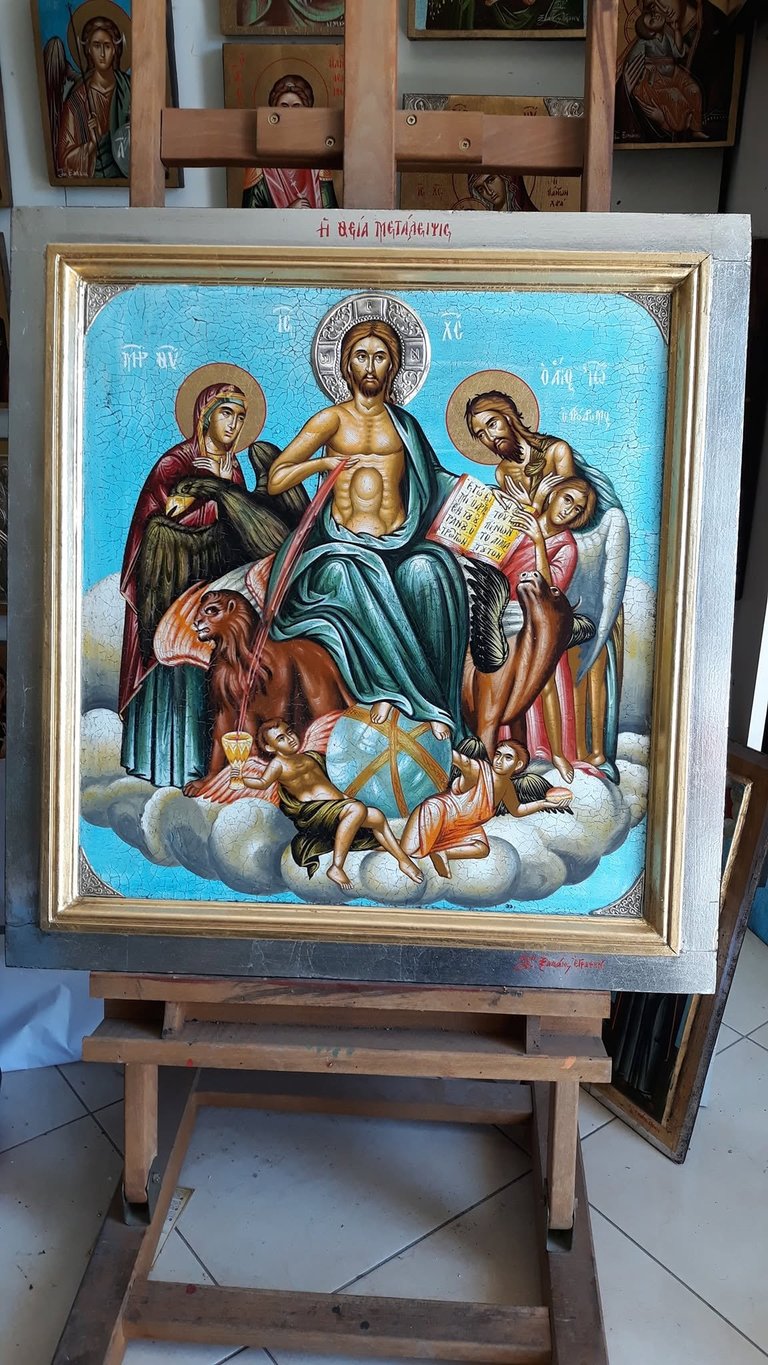 Orthodox icon depicting Jesus Christ enthroned in heaven with Virgin Mary, saints, and cherubs among clouds, displayed on wooden easel