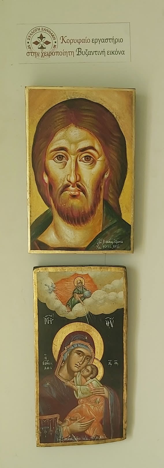 Two Byzantine religious icons mounted on a wall. Top icon shows a bearded male saint with a gold background. Bottom icon depicts Mary holding the Christ child with an angel above.