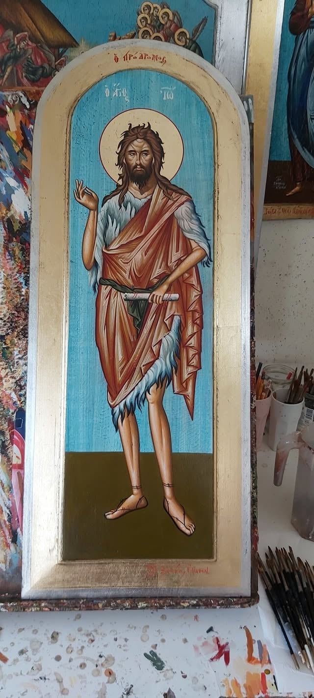 Orthodox religious icon depicting a bearded saint with halo in red robes against blue background on wooden panel