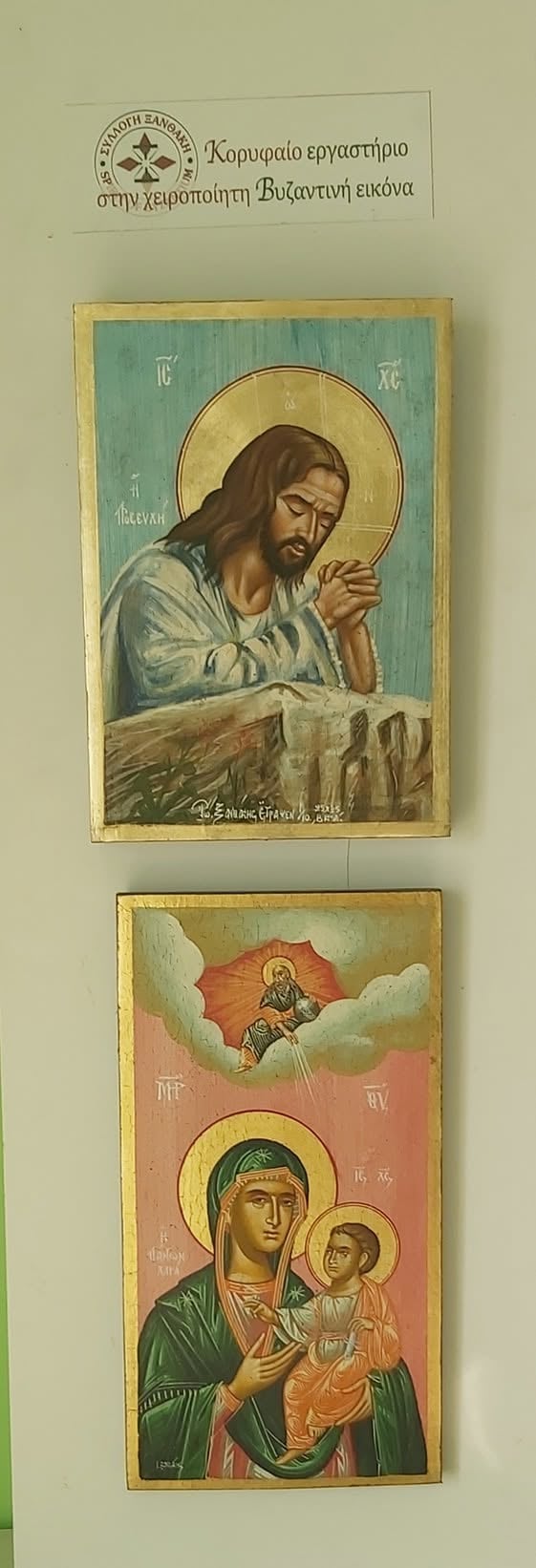 Two Byzantine religious icons displayed on a wall with Greek text header. Top: Christ icon with halo. Bottom: Virgin Mary holding Christ Child icon.