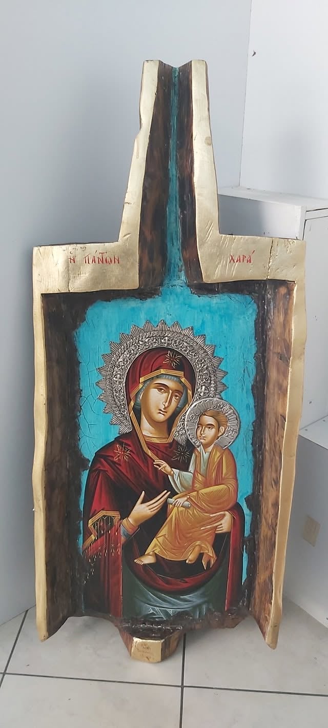 Orthodox religious icon depicting Mary holding baby Jesus with halos, mounted on wooden panel with turquoise background