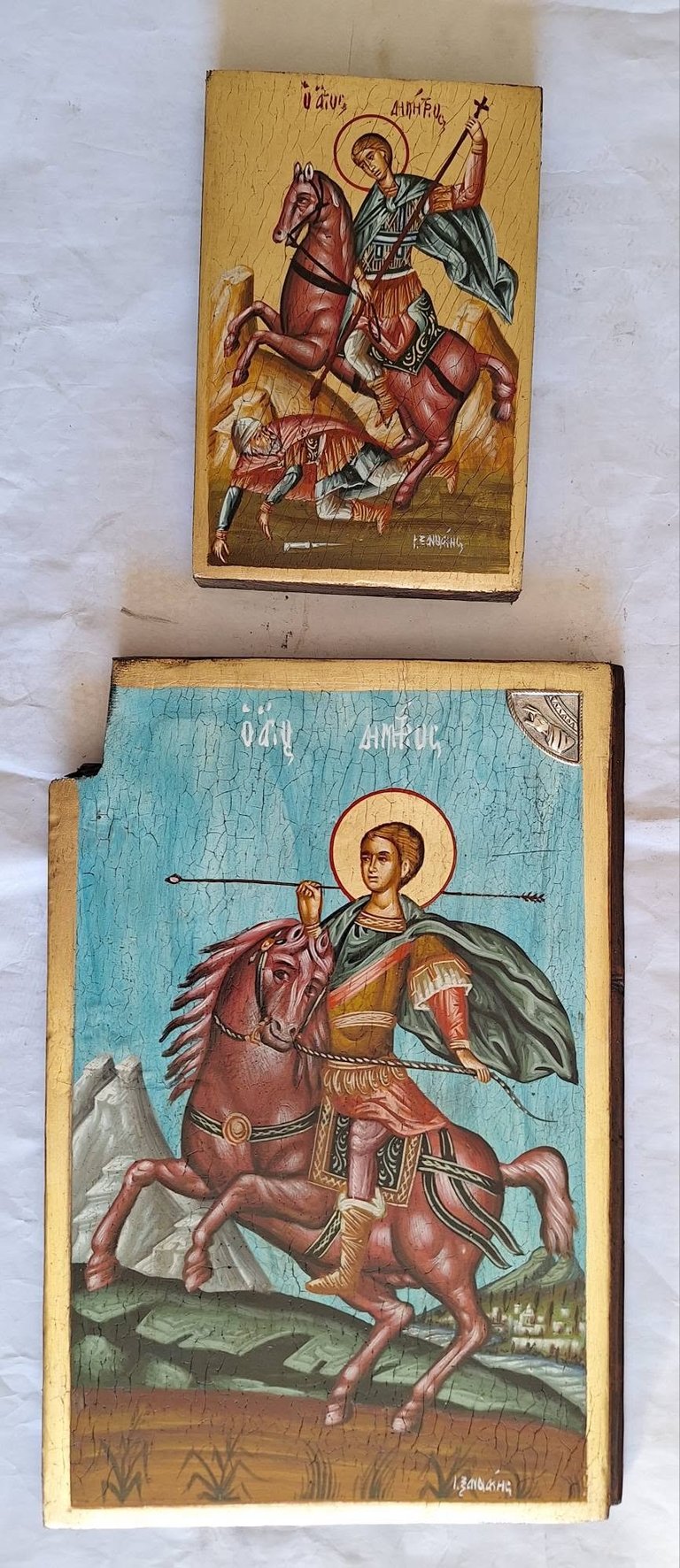 Two Orthodox Christian icon paintings on wooden panels depicting Saint George on horseback slaying a dragon, with gold halos and traditional religious iconography