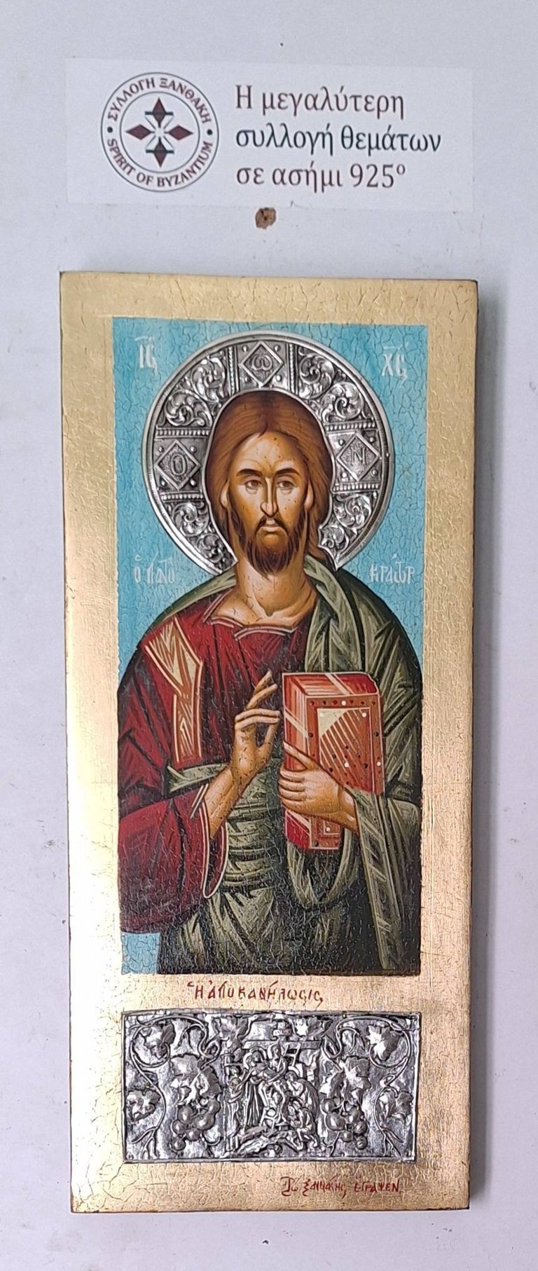 Byzantine religious icon depicting Christ Pantocrator with halo, holding a jeweled gospel book, wearing red and green robes on gold leaf panel