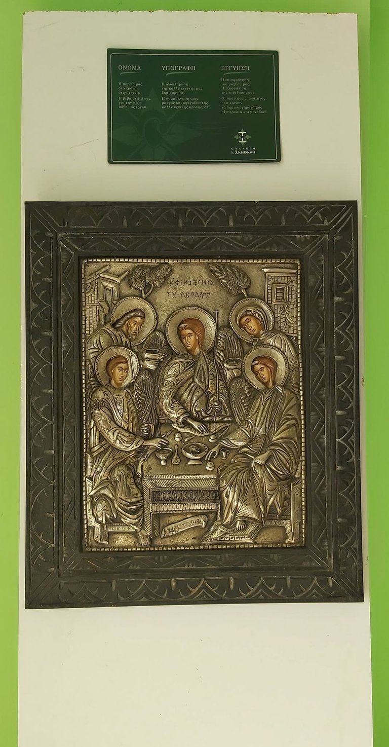 Russian Orthodox icon with gilt relief showing Virgin Mary and angels in ornate green frame with Cyrillic text placard above