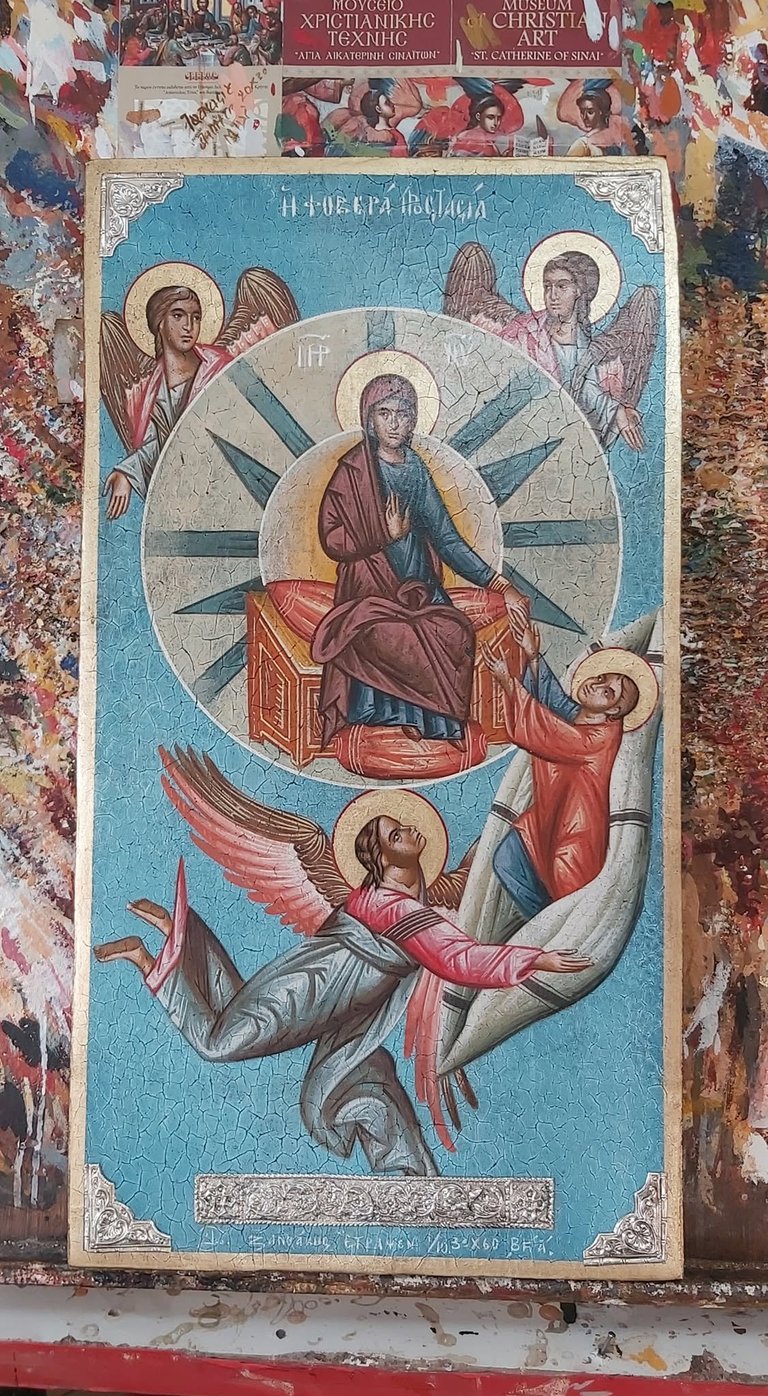 Byzantine religious icon depicting Christ in center surrounded by four angels, with Greek text at top, blue background, displayed among other religious texts and ornate decorative elements