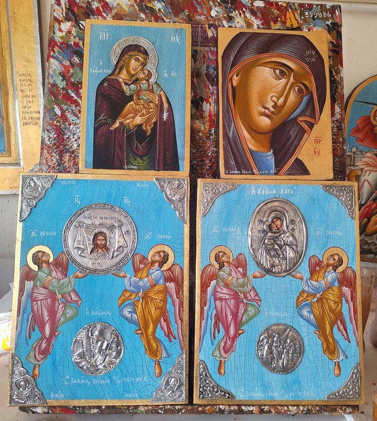 Two pairs of Orthodox religious icons displayed against patterned fabric, featuring blue backgrounds, portraits of Mary and Jesus, and angels with silver medallions