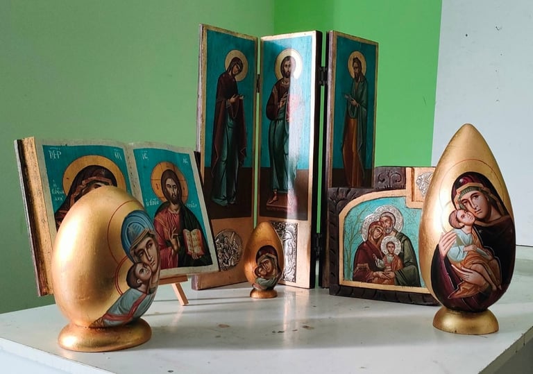 Collection of religious icons and figurines displayed on a white surface against a green wall background