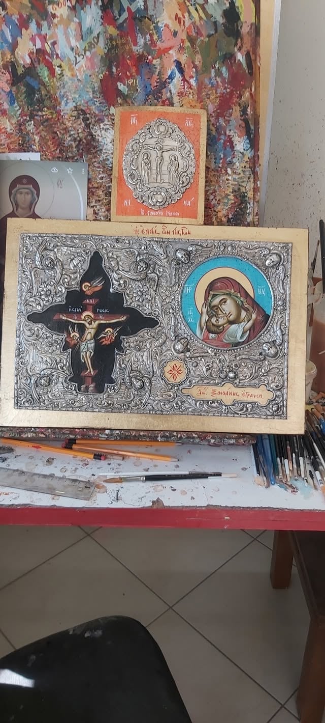 Eastern Orthodox religious icon artwork displayed on table with ornate cross and Madonna figure surrounded by intricate decorative patterns