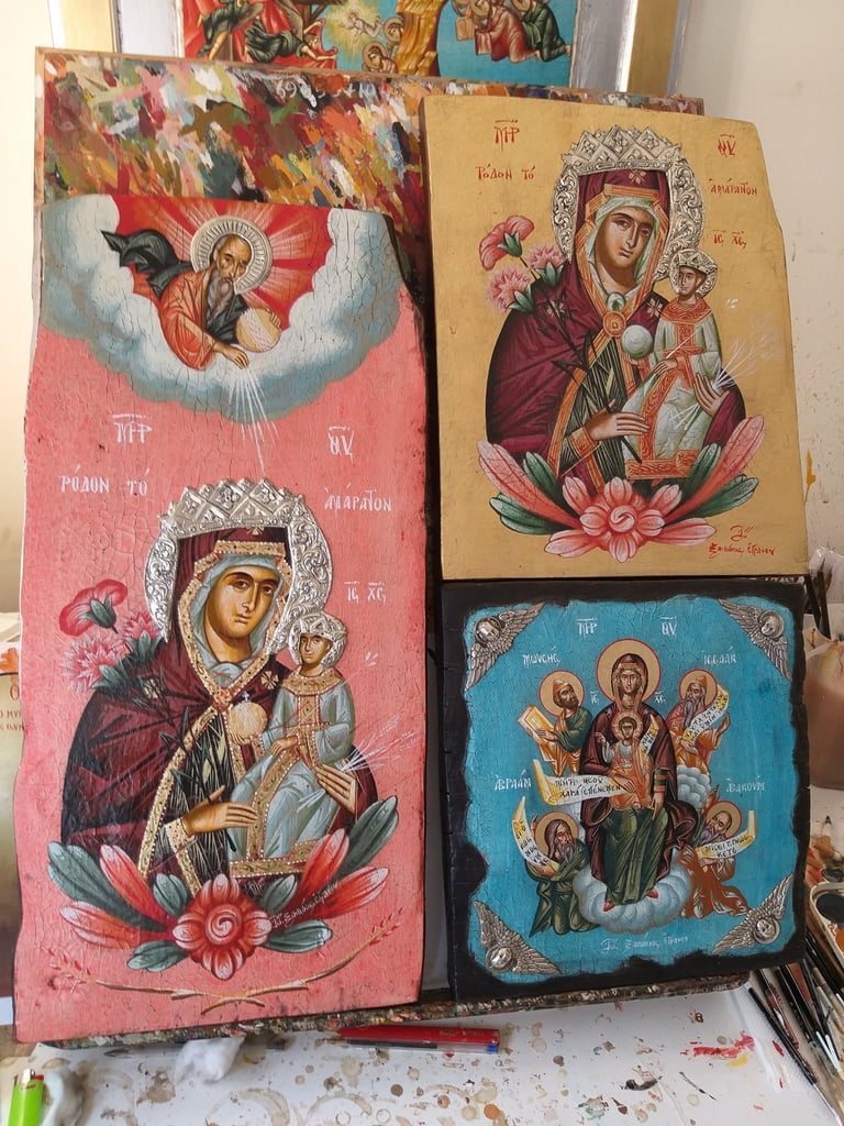 Three Orthodox religious icons displayed featuring Byzantine-style depictions of Mary and Jesus with ornate floral and metallic embellishments on pink, tan, and blue backgrounds