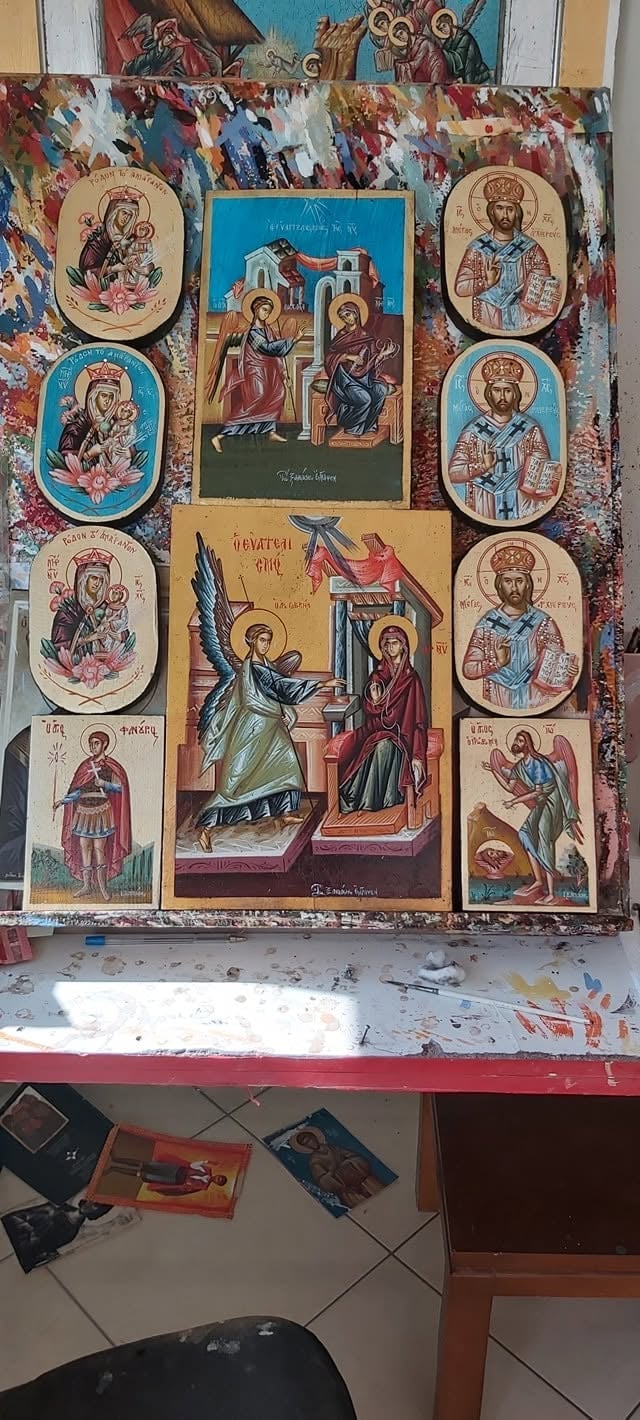 Wooden religious icon display featuring Orthodox Christian imagery with multiple painted panels of saints and biblical scenes arranged on a weathered board.